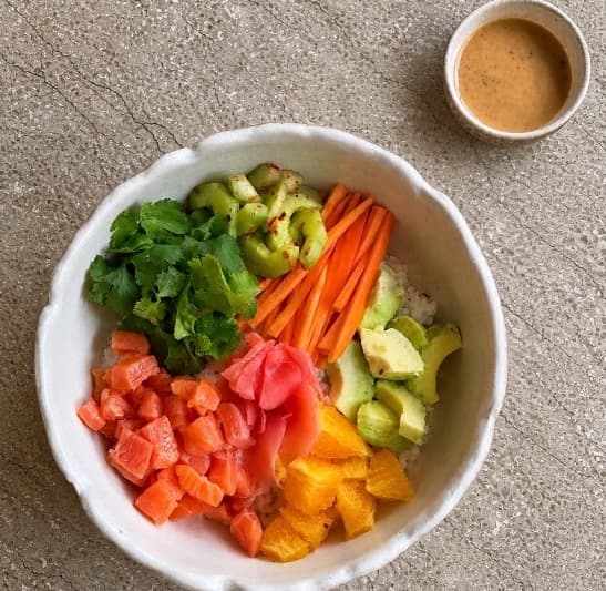 Salmon poke  — A vibrant poke bowl with fresh salmon, Japanese rice, avocado, orange, cucumber, carrot, cilantro, a