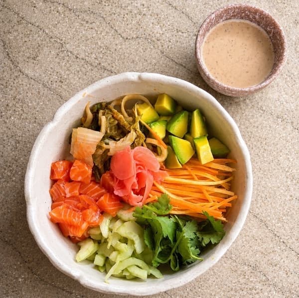 Salmon poke  — A vibrant poke bowl with fresh salmon, Japanese rice, avocado, orange, cucumber, carrot, cilantro, a