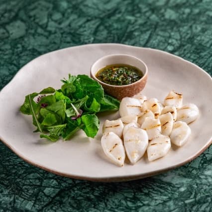Squid — Tender grilled squid served with fresh herbs and sauce. Light, juicy, and perfectly charred.