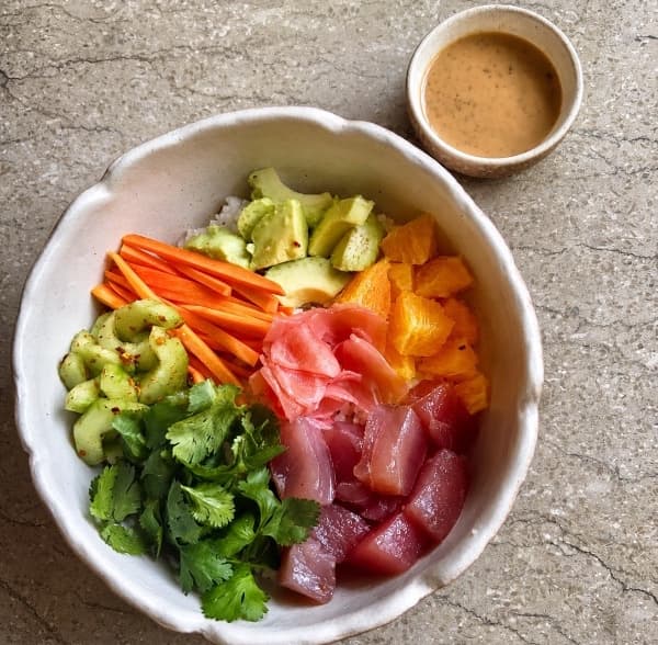 Tuna poke  — Fresh tuna served over Japanese rice with avocado, orange, cucumber, carrot, cilantro, and marinated
